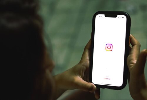 Mano sosteniendo un teléfono con una app de redes sociales, marketing para psicólogos