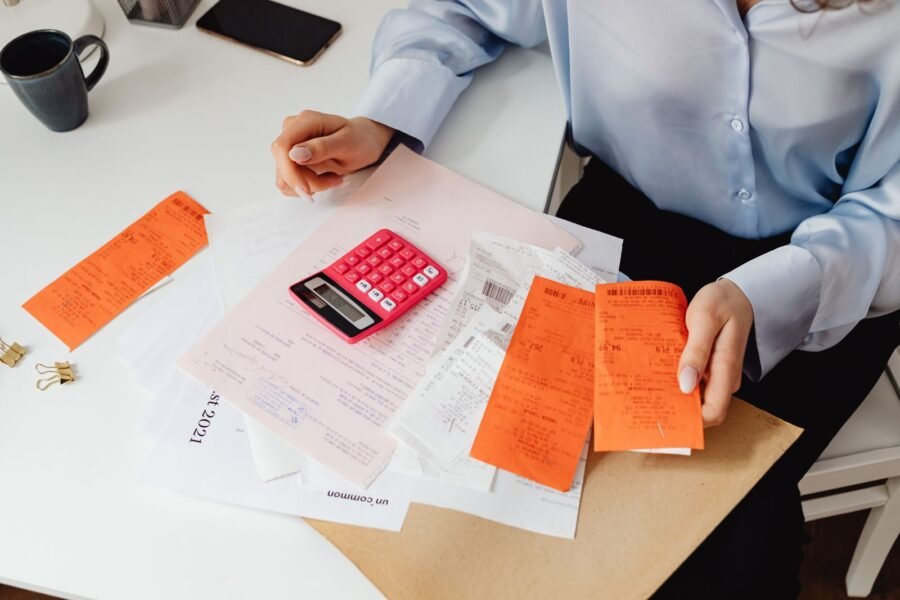 Persona sosteniendo recibos y usando una calculadora para facturación